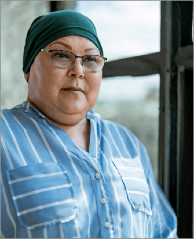 Lisa, a woman receiving TRODELVY. Lisa is a Latina woman wearing a headscarf, glasses, and a blue shirt with white stripes.