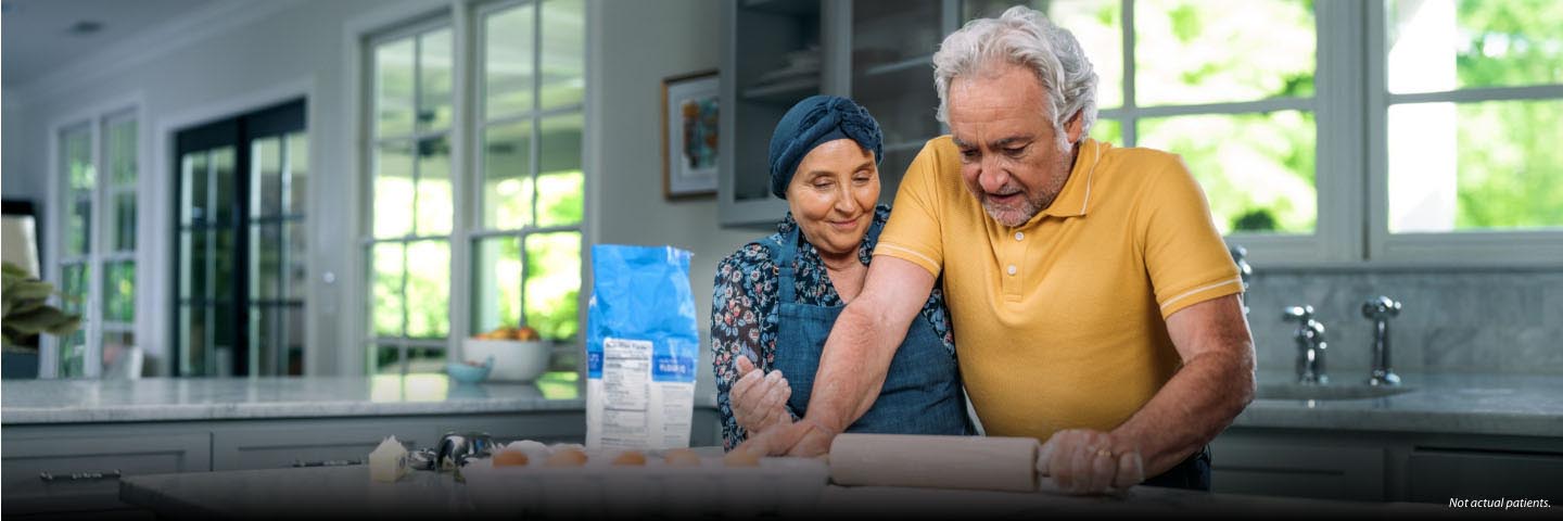 A Hispanic man and woman in their 60s are standing at their kitchen counter cooking together at home. She is wearing a head scarf and an apron. They look content. Not actual patients but actual stories.